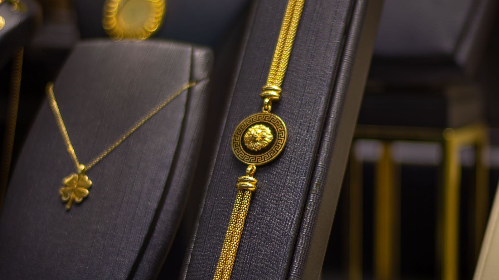 A gold necklace and bracelet on dark display stands in a jewellery store